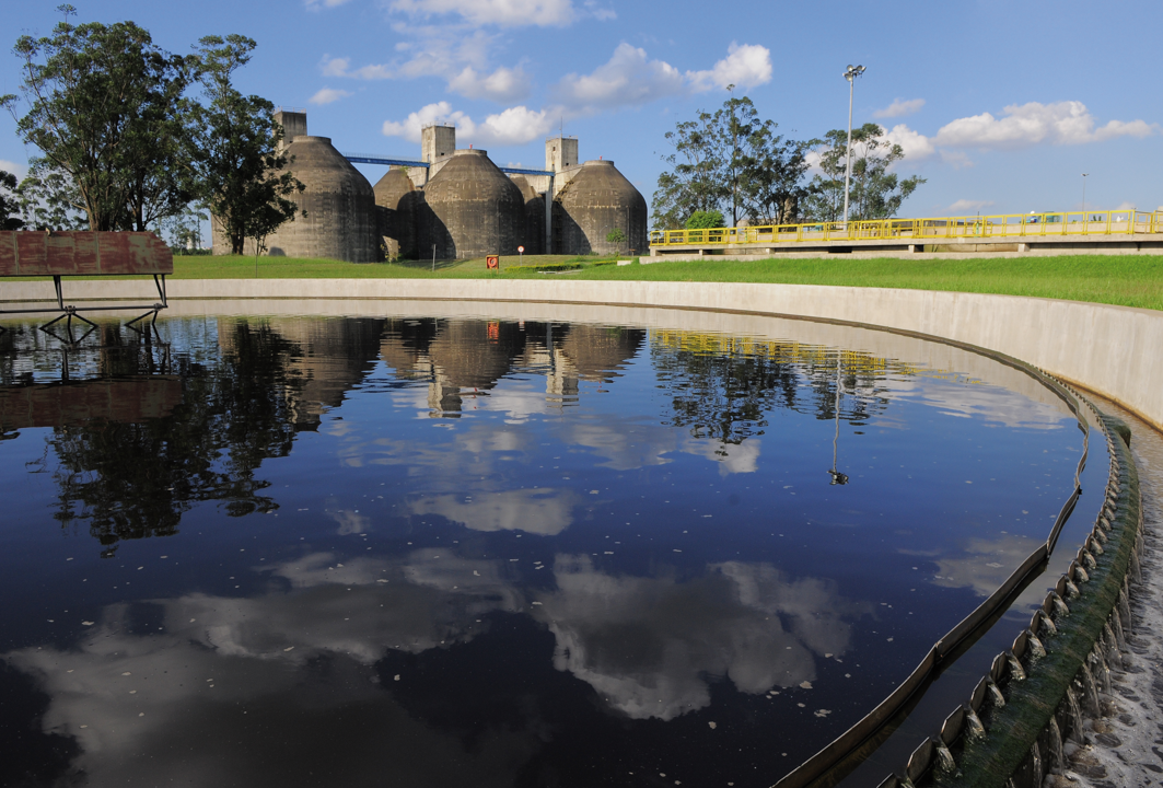 Circular wastewater treatment basin with industrial tanks at a SABESP facility in São Paulo state, Brazil.
