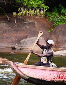 man in canoe idb invest stories suriname