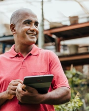 a man with tablet smiling in a plant shop 