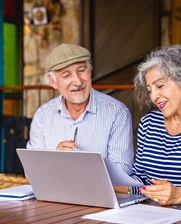 dos adultos mayores, un hombre y una mujer, mirando a una computadora portatil 