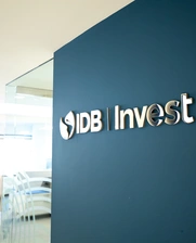 IDB Invest logo displayed on a blue wall in an office