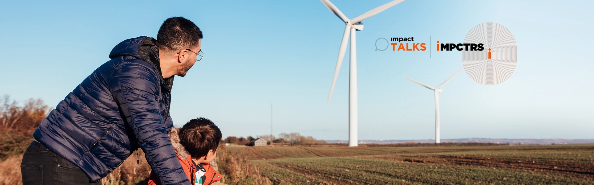 Banner image of a father and his son at the field looking at a windmill.