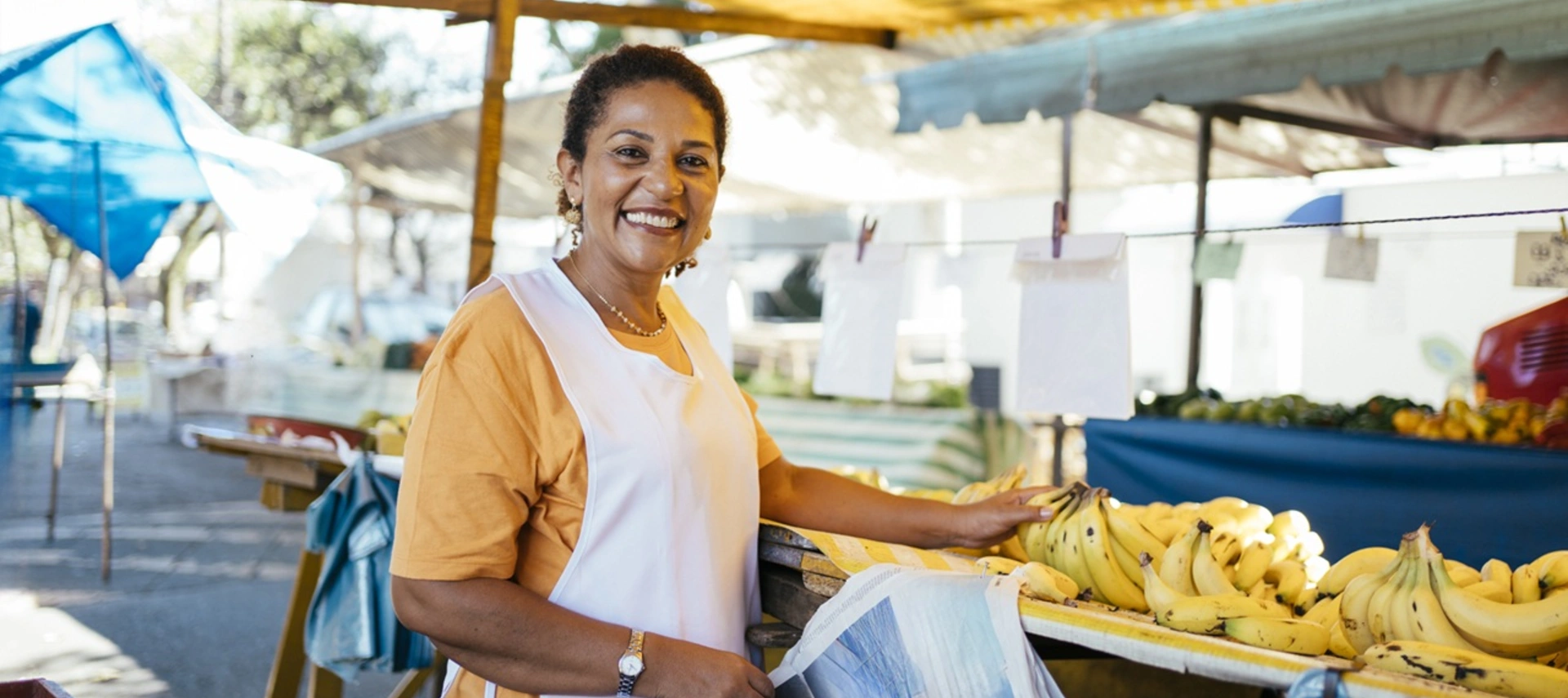 Image of a smiling woman selling bananas at a street market