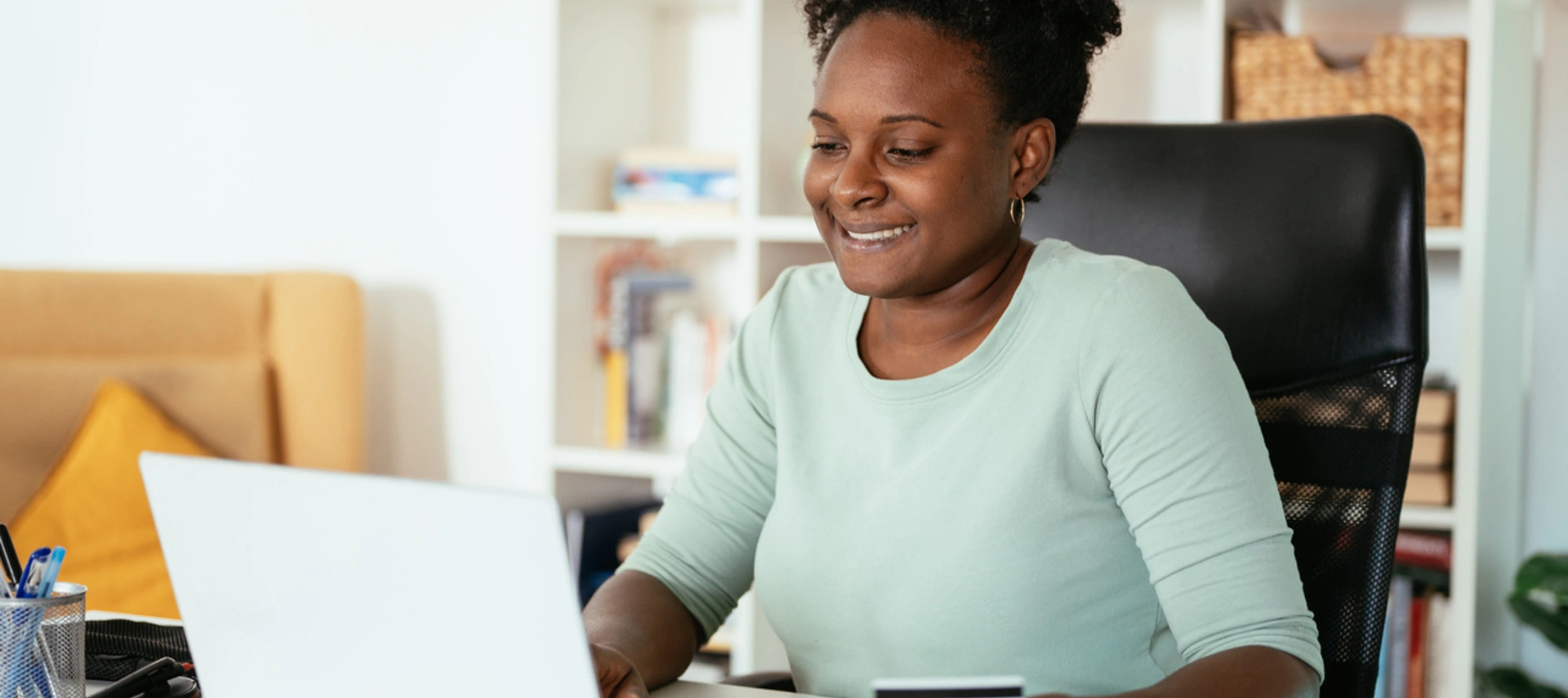 Woman looking at her compoter using  a credit card 