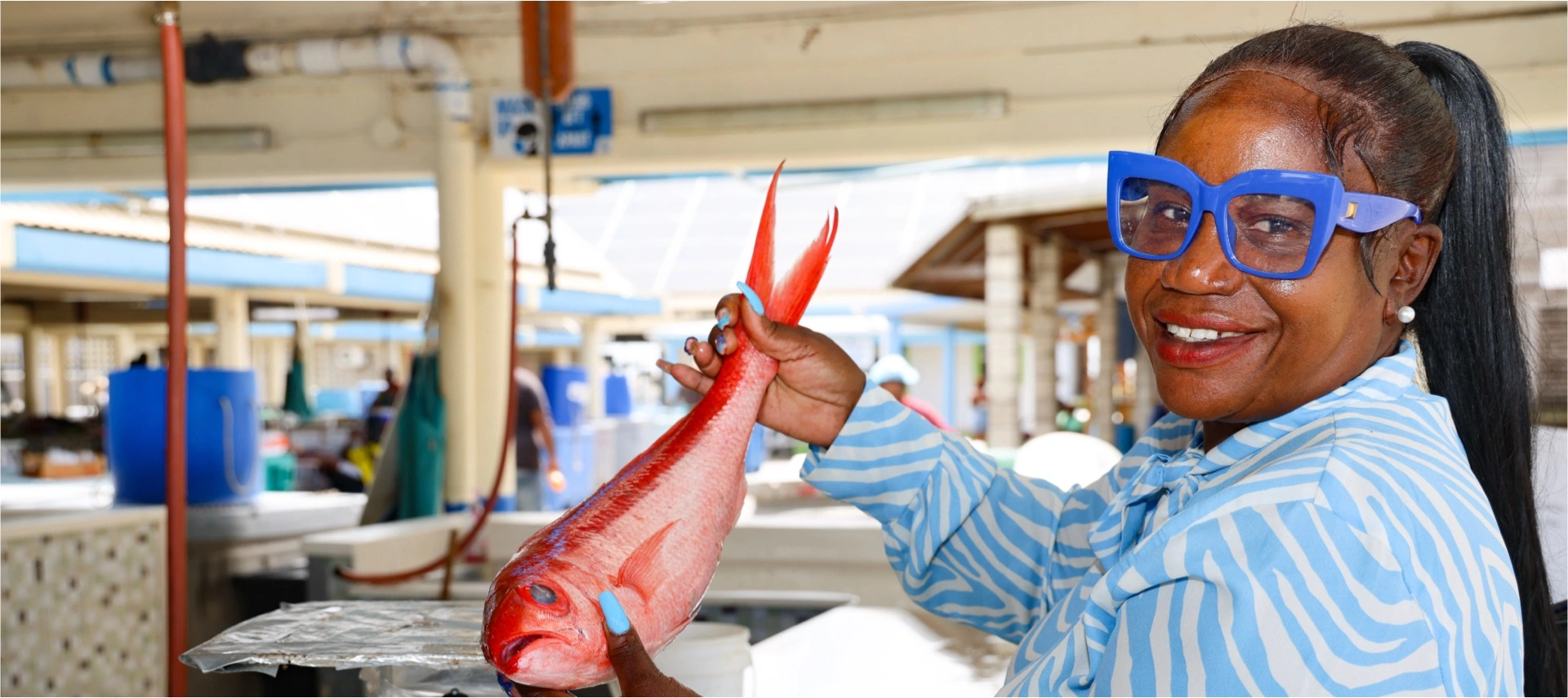 Image of a black woman holding a fish at a Barbados market place