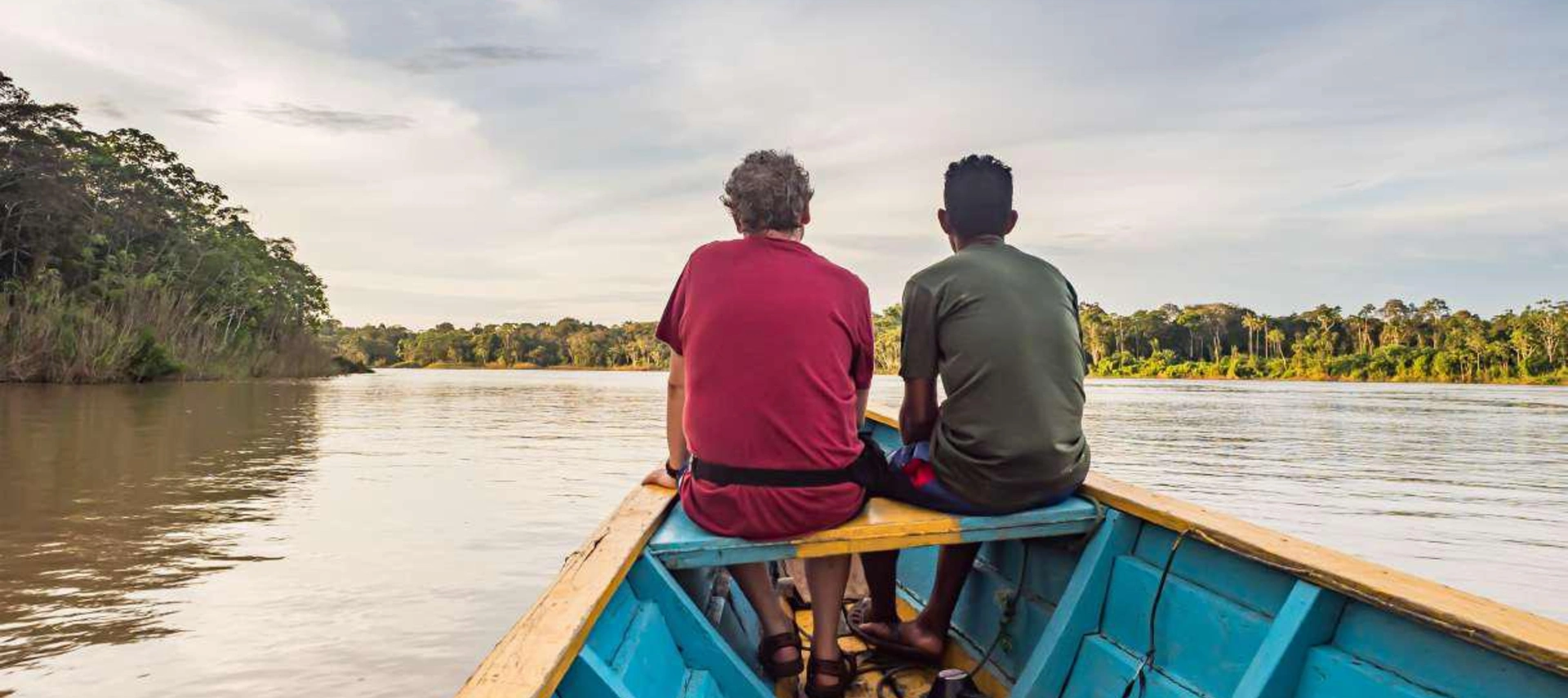 Image of two fishermen navigating the Amazon river on their boat