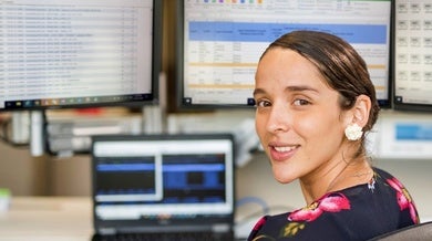 Una mujer sentada frente a monitores de computadora