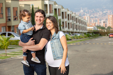 Happy family posing with houses in the background.