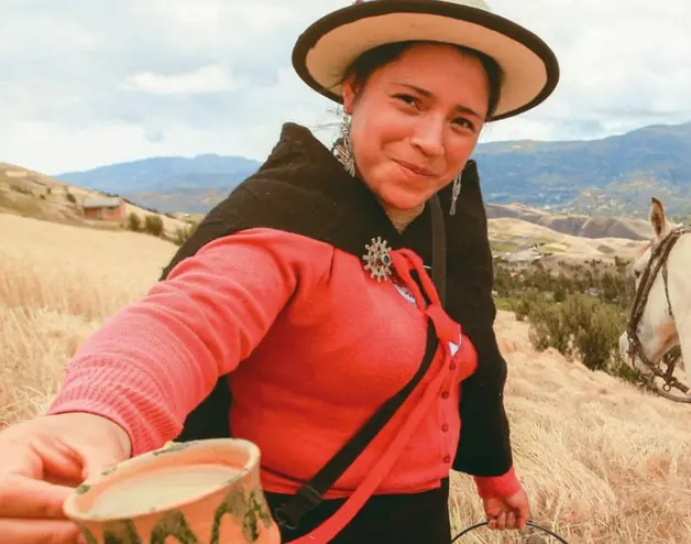 Image of an Ecuadorian farmer woman offering a cup of fresh milk