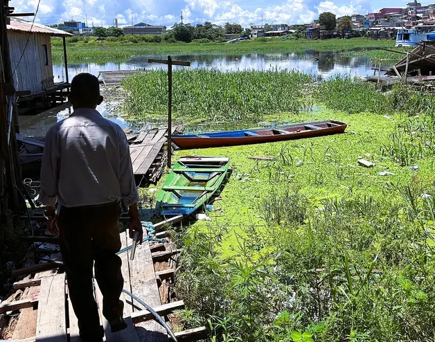 Um homem caminha perto da água em uma favela em Manaus