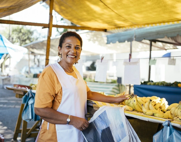 Image of a smiling woman selling bananas at a street market