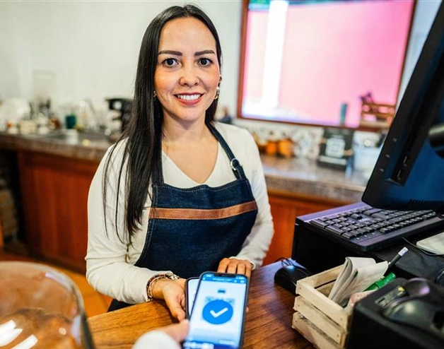A woman in a commercial shop holds an electronic payment reader.