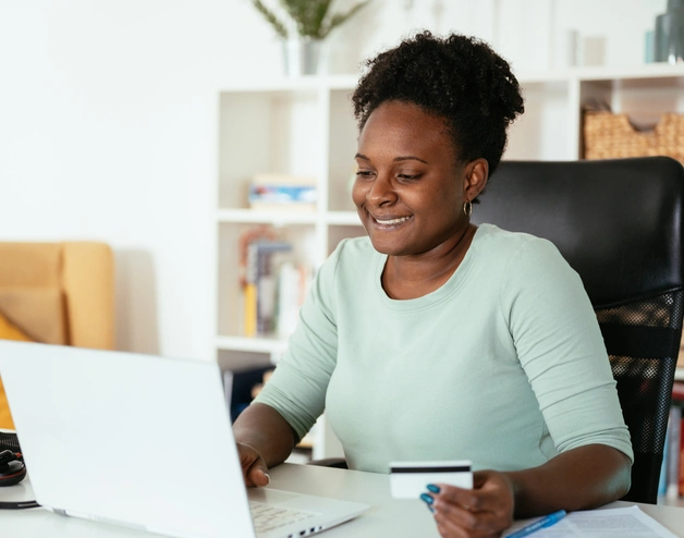 Woman looking at her compoter using  a credit card 