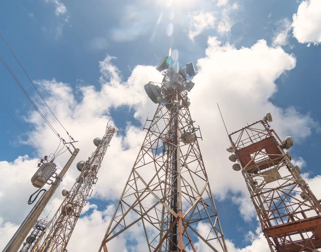 Multiple telecommunications towers equipped with antennas and transmission equipment, symbolizing broadband and digital infrastructure.