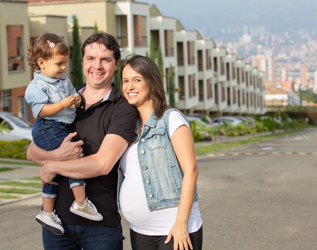 Happy family posing with houses in the background.