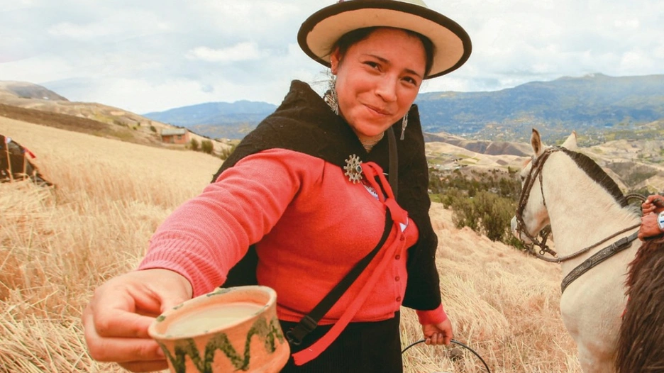 Image of an Ecuadorian farmer woman offering a cup of fresh milk