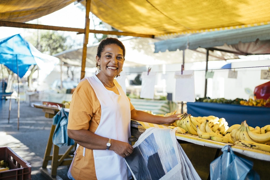 Image of a smiling woman selling bananas at a street market