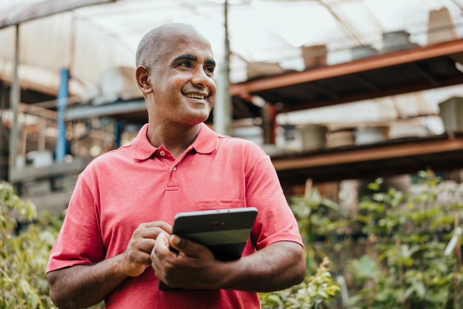 a man with tablet smiling in a plant shop 
