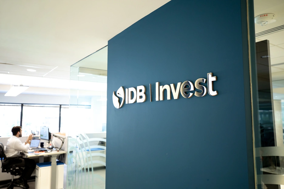 IDB Invest logo displayed on a blue wall in an office